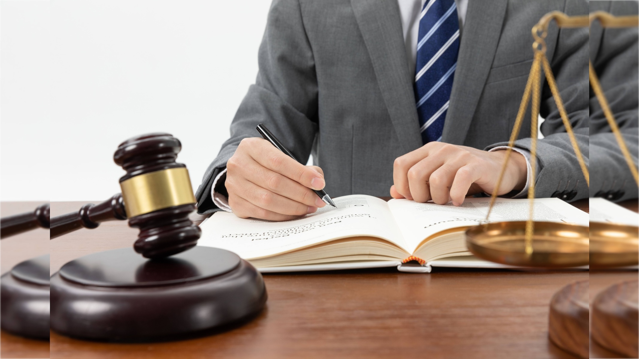 closeup-shot-person-writing-book-with-gavel-table_2_16x9