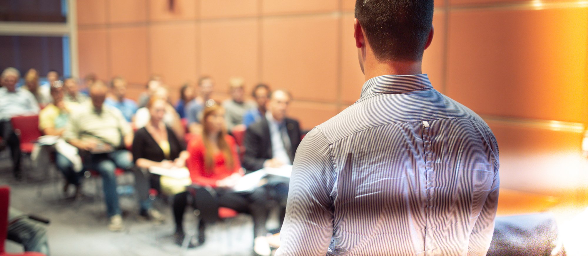 Public speaker giving talk at Business Event. Speaker giving a talk on corporate business conference. Unrecognizable people in audience at conference hall. Business and Entrepreneurship event.